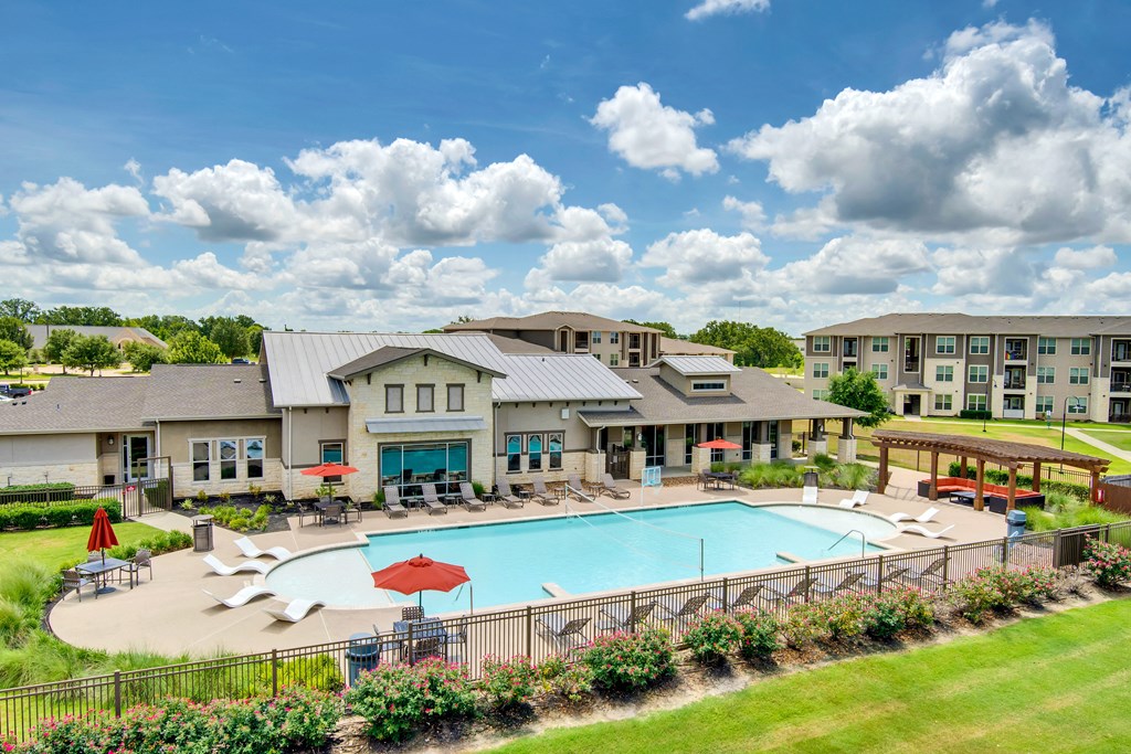 a swimming pool with lounge chairs and umbrellas in front of a building