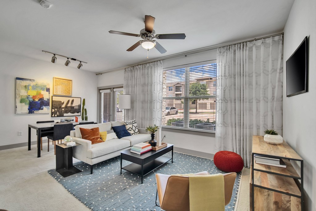 a living room with a large window and a ceiling fan