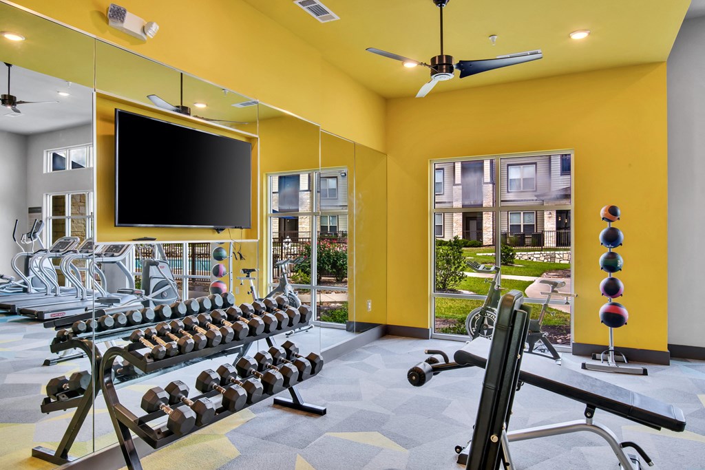 a gym with weights and a tv on the wall