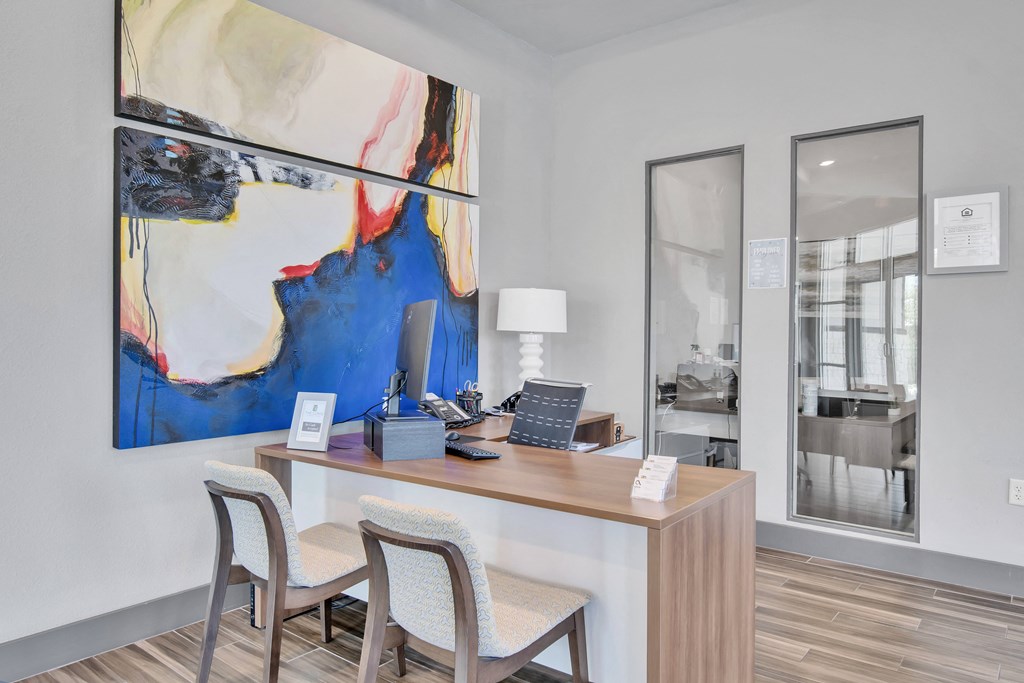 a desk with two chairs and a large painting on the wall