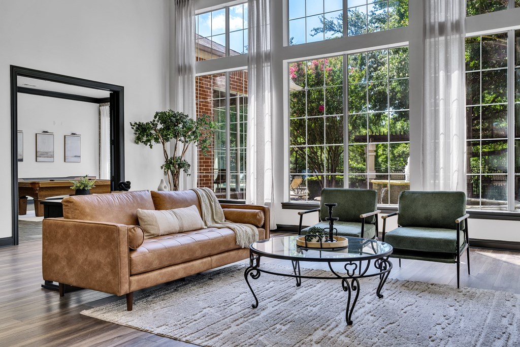 a living room with a couch and chairs and large windows
