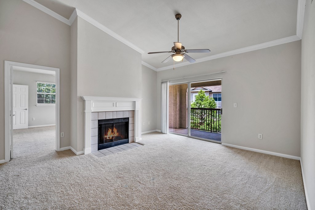 an empty living room with a fireplace and a ceiling fan