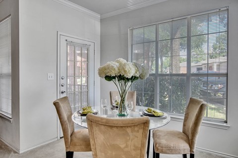 Dining area with round glass table and upholstered chairs at Seven Oaks Apts Apartments, Texas