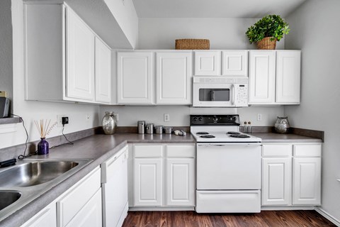 a kitchen with white cabinets and white appliances and a sink