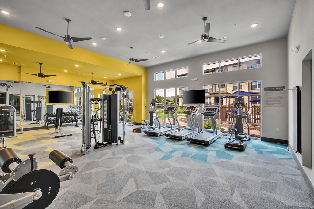a gym with weights and cardio equipment in a building with windows