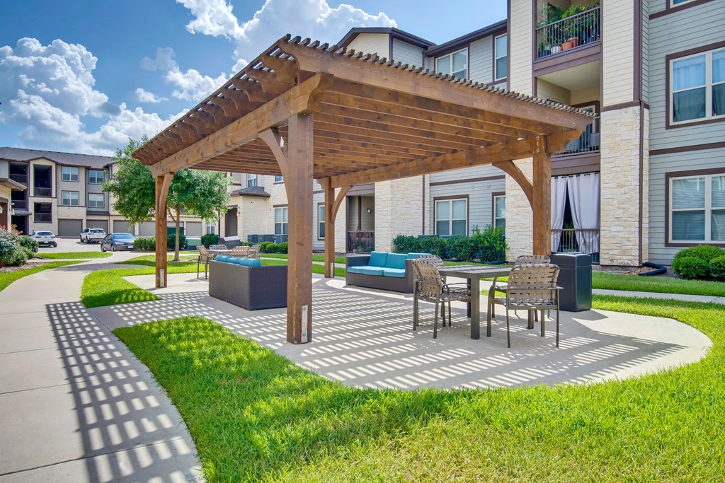 a patio with a table and chairs under a wooden pavilion