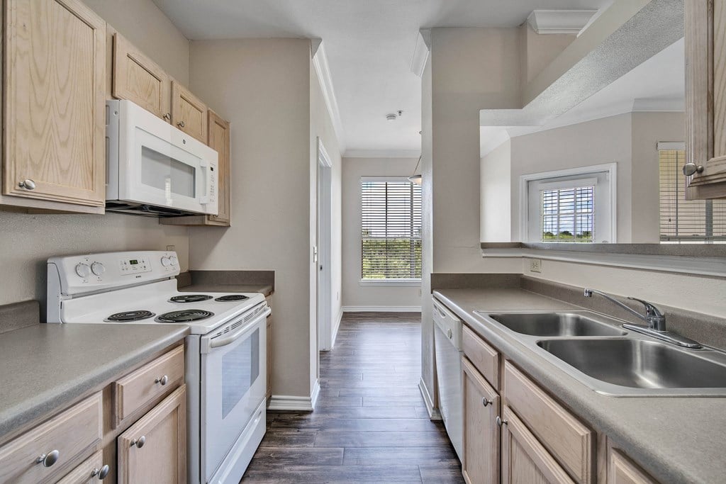 an empty kitchen with wooden cabinets and white appliances
