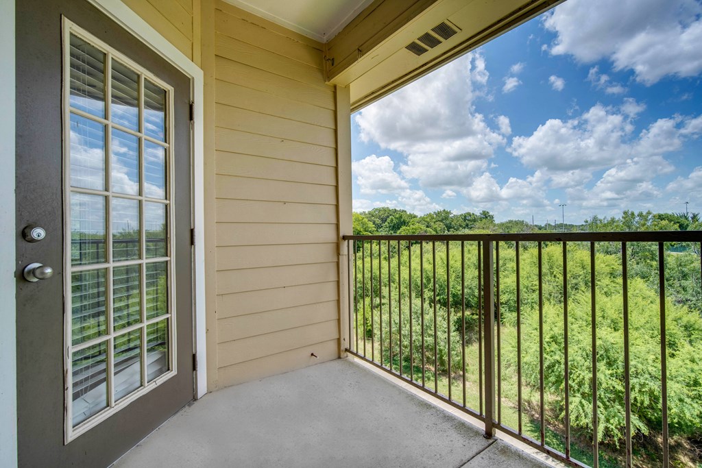 a balcony with a view of a field and a glass door