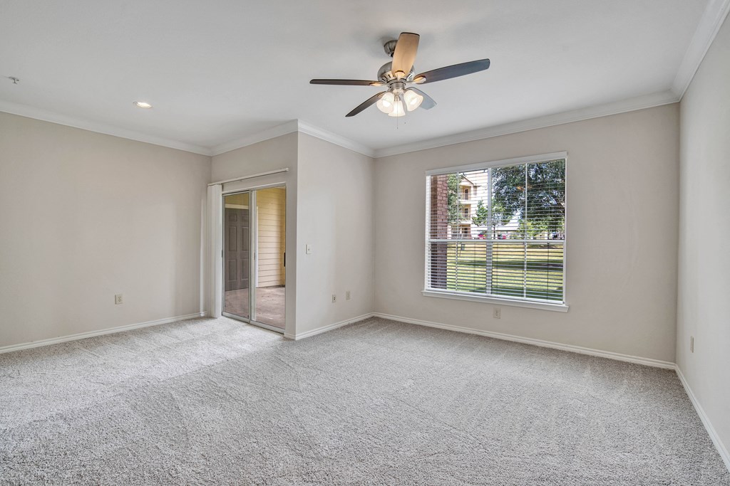 an empty living room with a ceiling fan and a window
