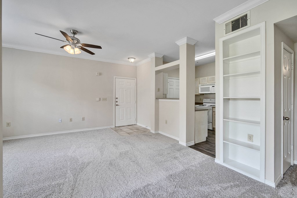an empty living room with a closet and a ceiling fan