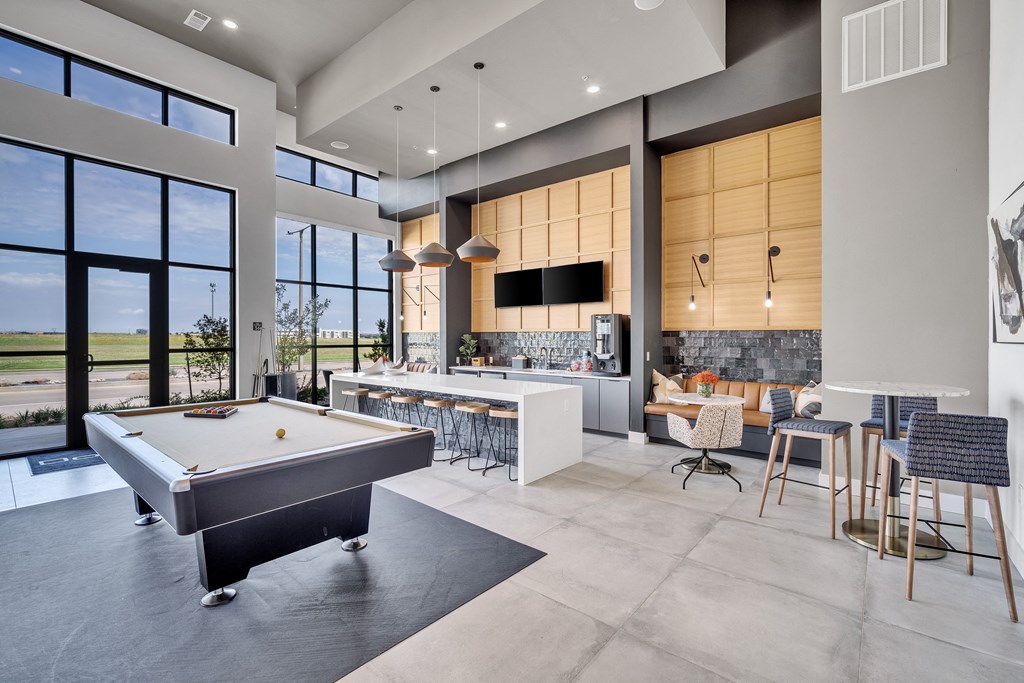 a pool table in the center of a living room with a kitchen and a bar