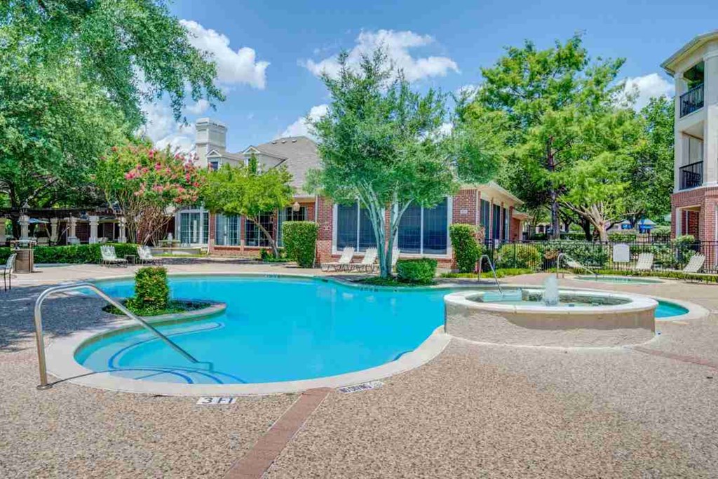 a swimming pool with a fountain in front of an apartment building