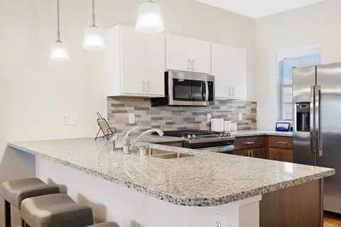 a kitchen with a granite counter top and a stainless steel refrigerator