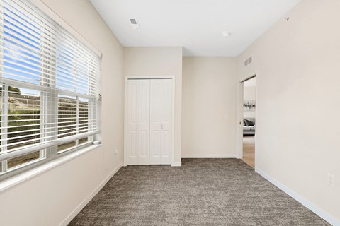 an empty bedroom with a large window and a door to a closet