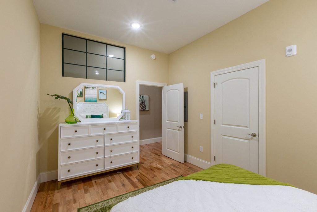 a bedroom with a white dresser and a bed with a green blanket