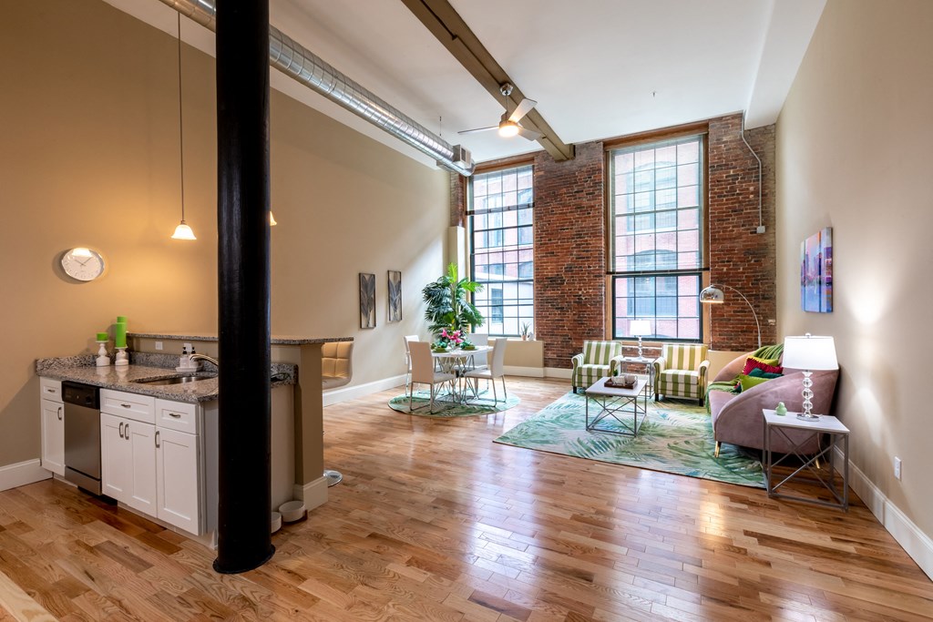 a living room with a kitchen and a exposed brick wall