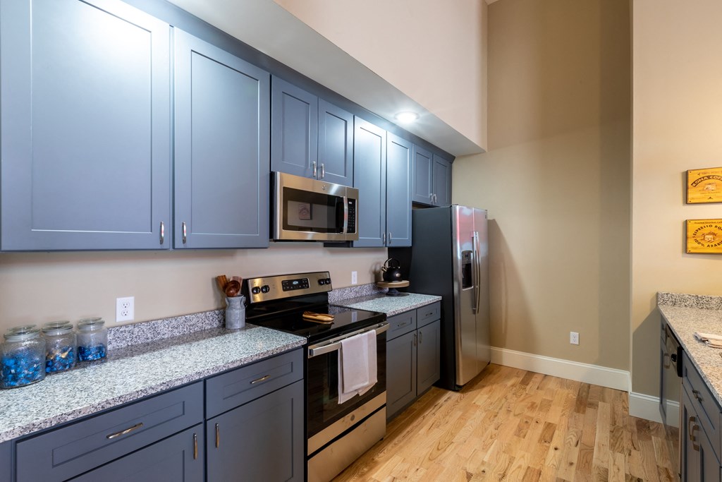 a kitchen with blue cabinets and stainless steel appliances and a wooden floor