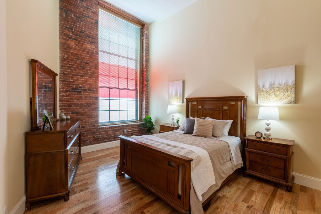 a bedroom with a bed and a brick wall