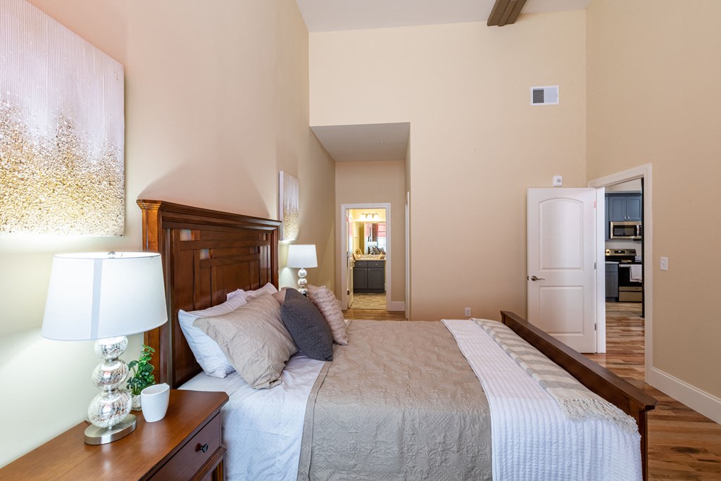 a bedroom with a bed and a dresser and a door to a bathroom