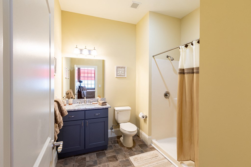 a bathroom with a shower toilet and sink and a blue vanity
