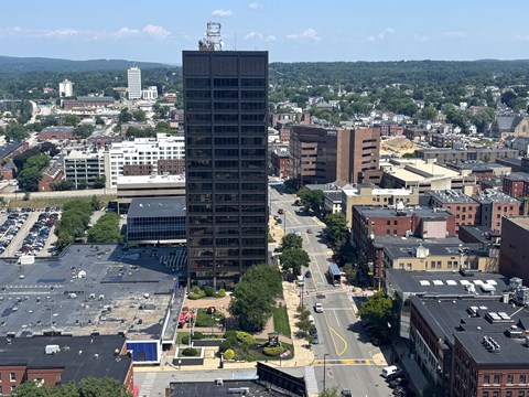 A tall building stands in the middle of a city intersection.