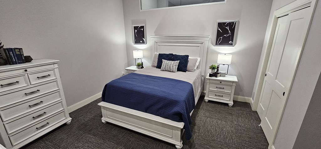 the master bedroom has a queen sized bed and white cabinets