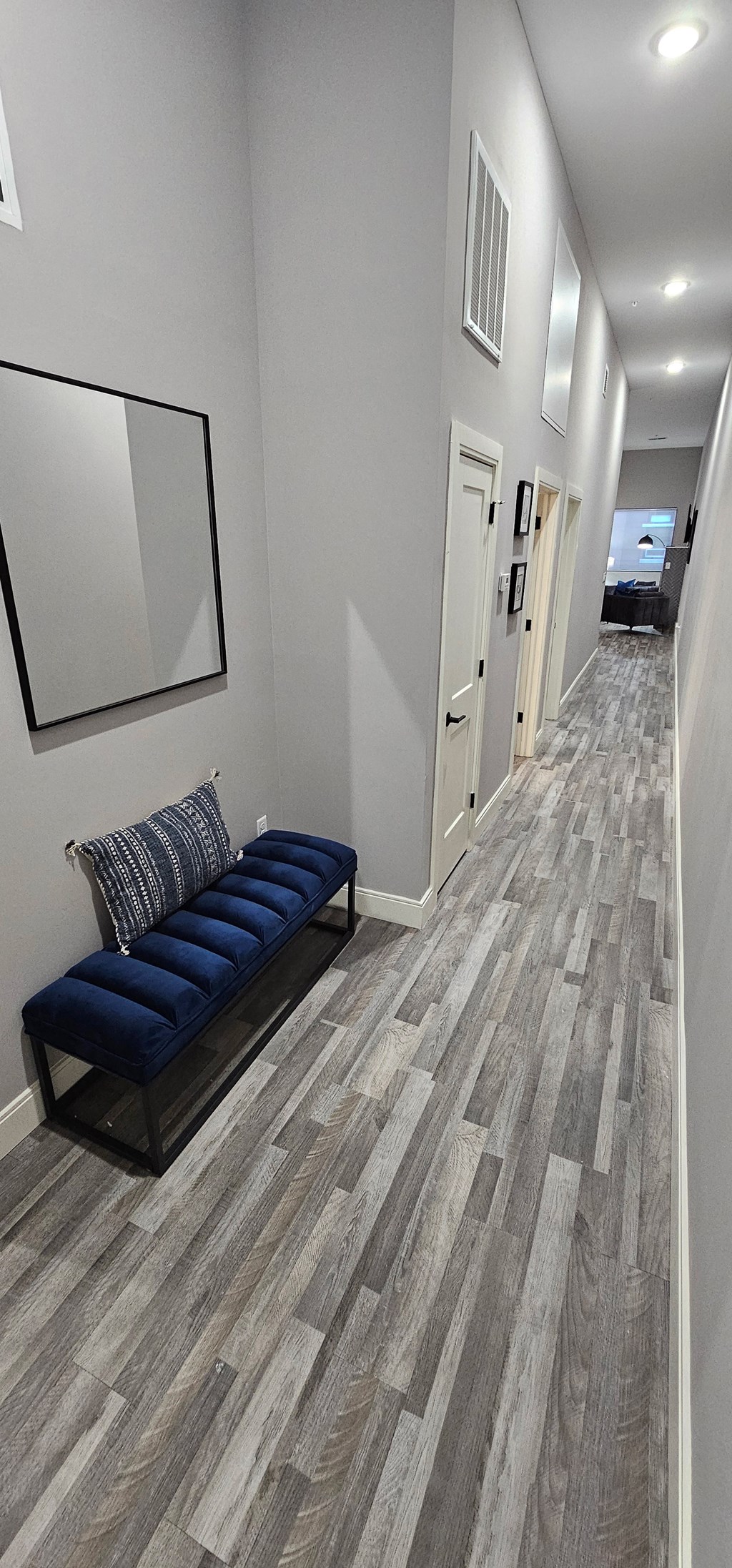 a living room with a couch and a hallway with white walls and wood floors