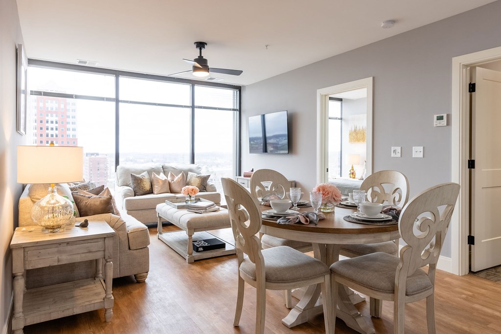 A dining room with a table set for two and a couch with pillows.