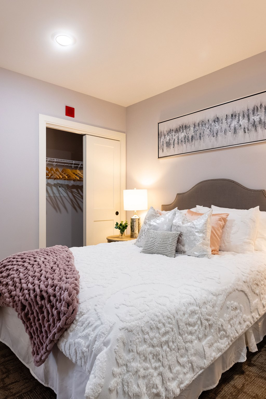 A bedroom with a bed, pillows, and a painting on the wall.