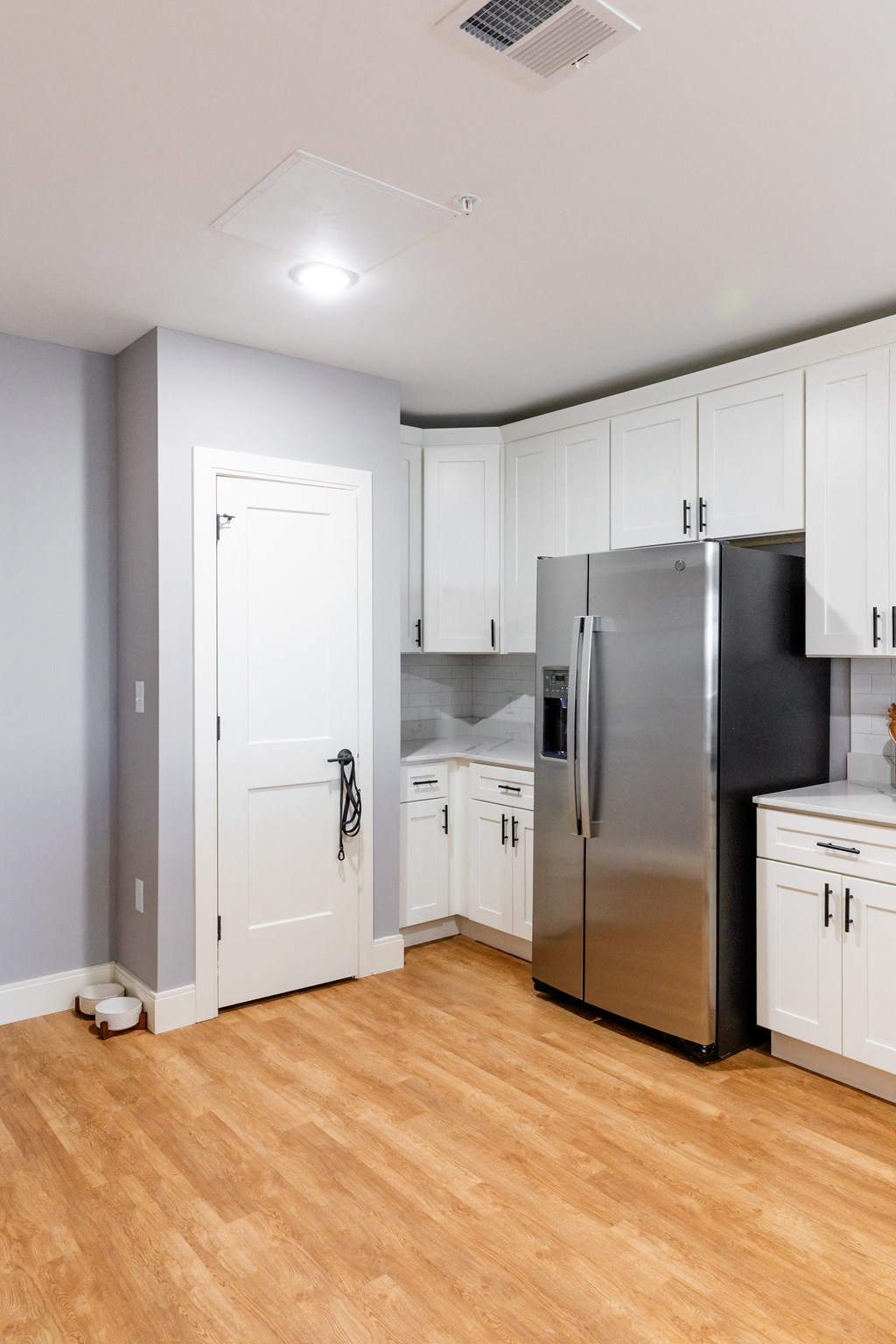 a kitchen with white cabinets and a stainless steel refrigerator