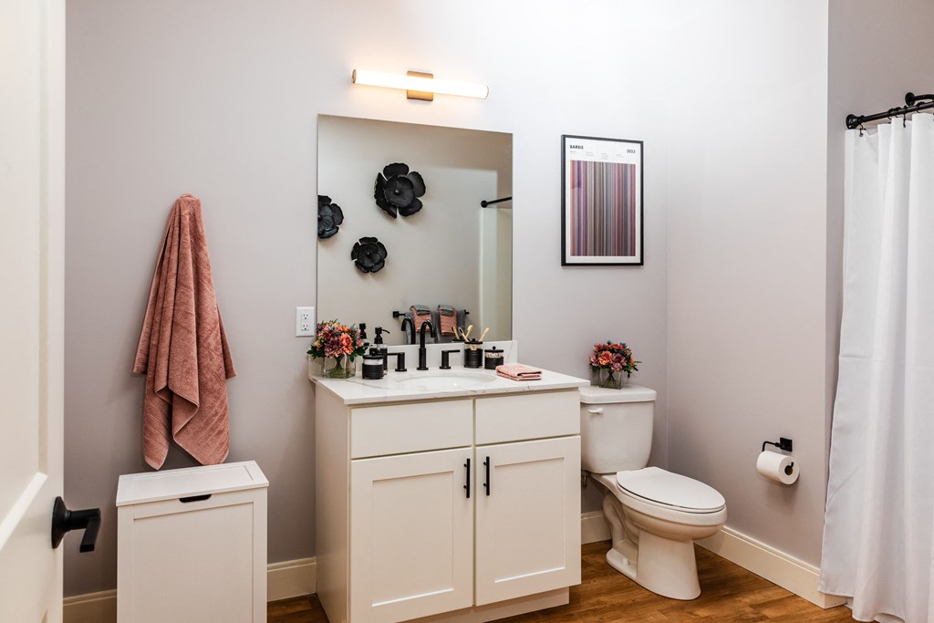 a bathroom with a white sink and toilet next to a white shower curtain and a pink towel