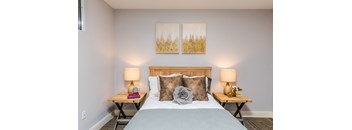 a bedroom with a bed two night stands and two paintings on the wall