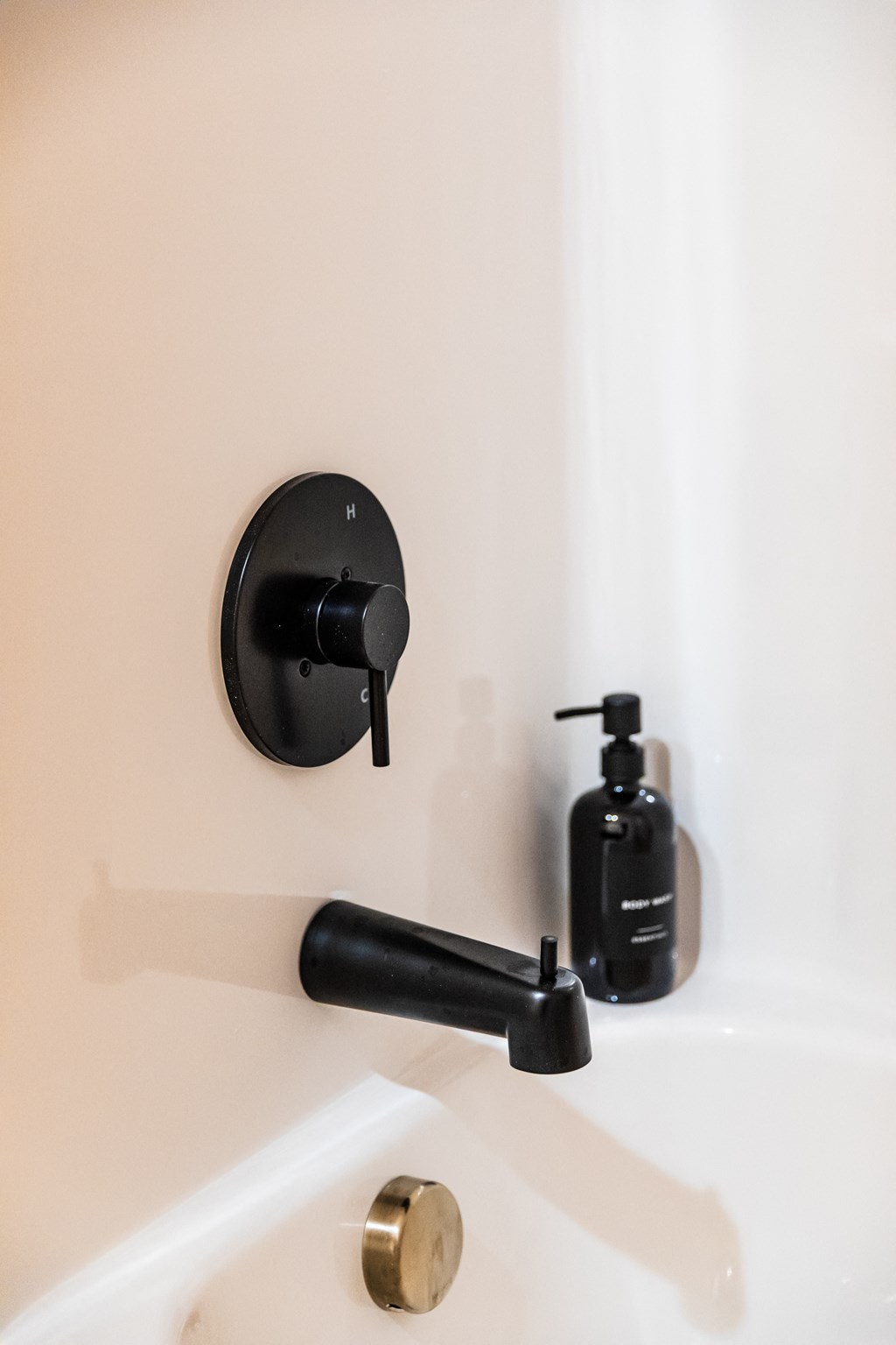 a bathroom with a black sink faucet and black soap dispenser