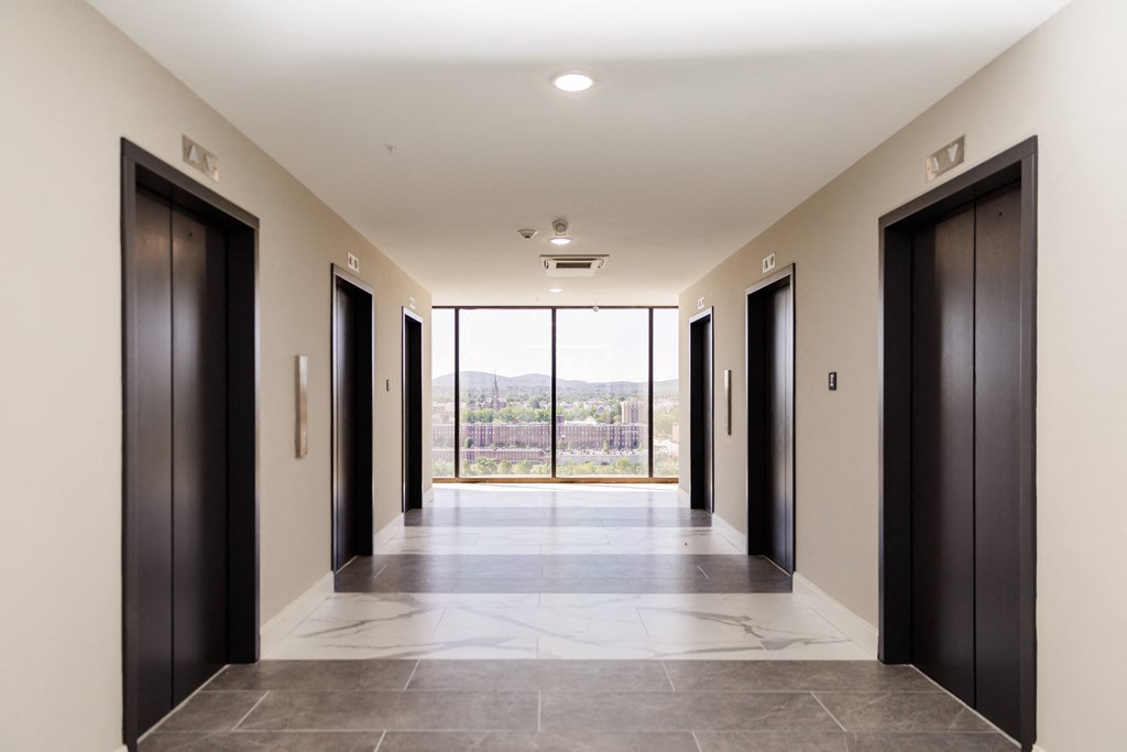 a long corridor with black doors and a view of the mountains