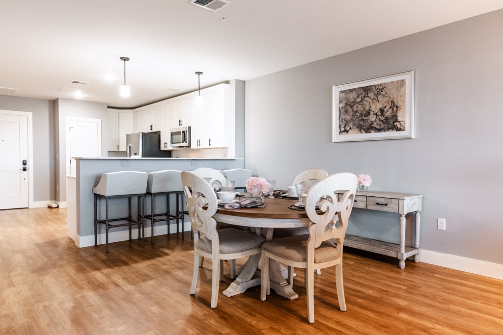 a dining area with a table and chairs and a kitchen in the background