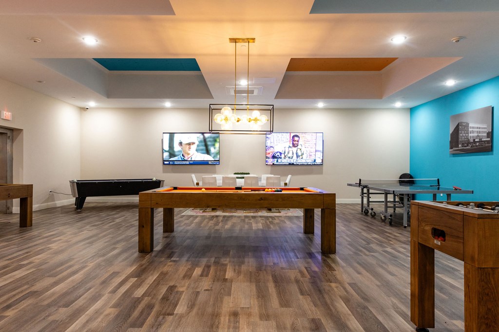 a billiards room with a pool table and televisions