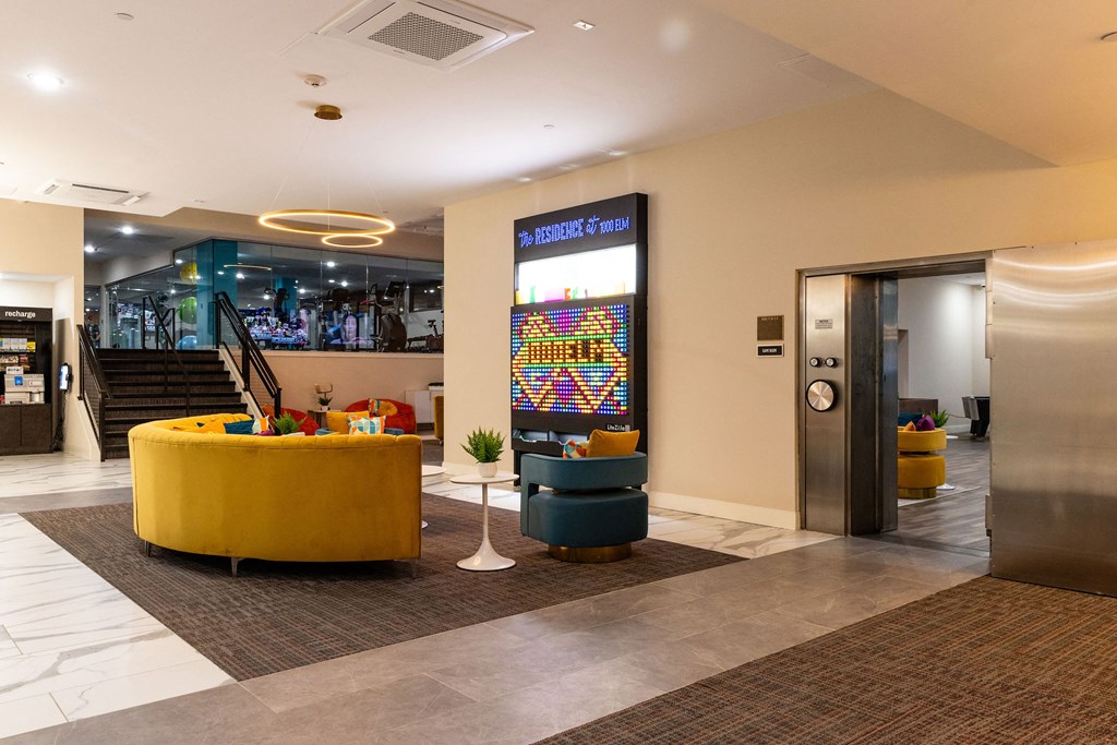 a lobby of a hotel with a yellow couch and chairs and a vending machine
