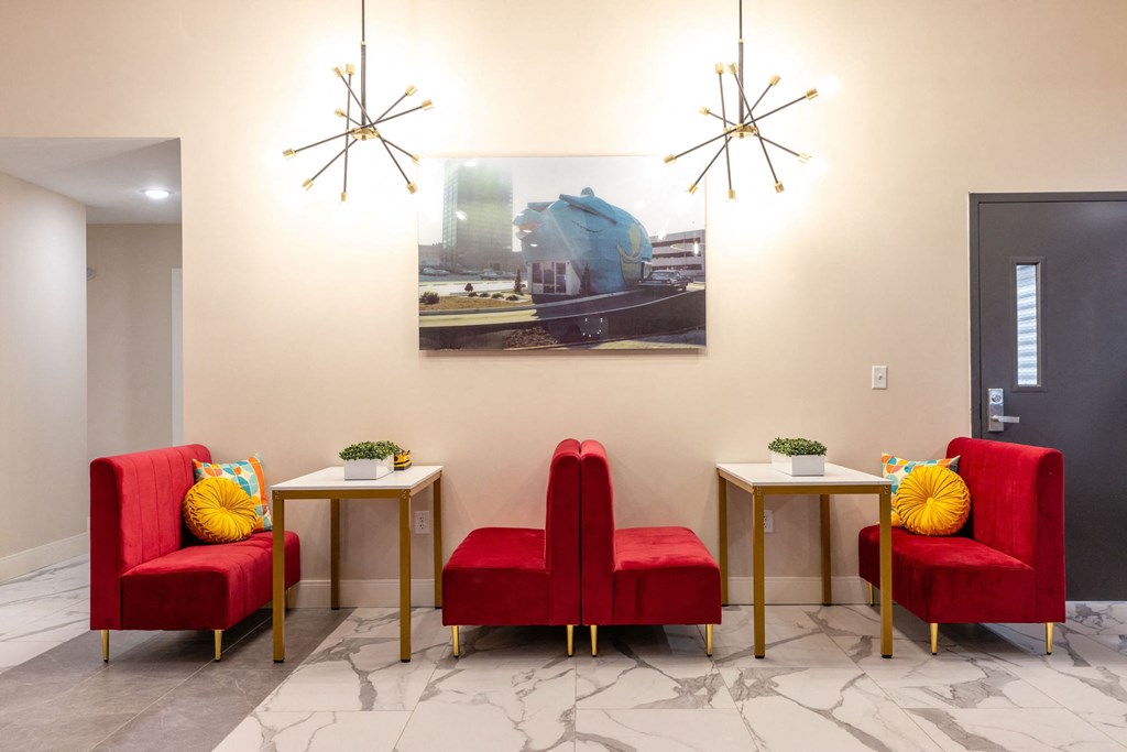 a living room with red chairs and a painting on the wall