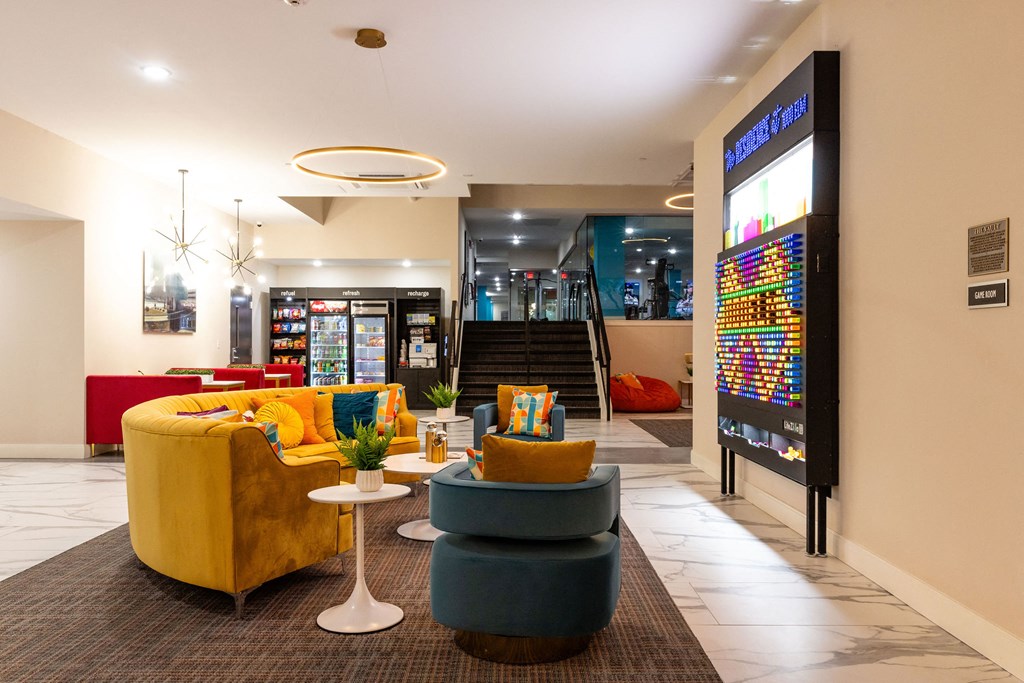the lobby of a hotel with couches and chairs and a vending machine