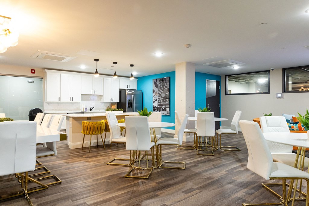a dining room with white chairs and tables and a kitchen