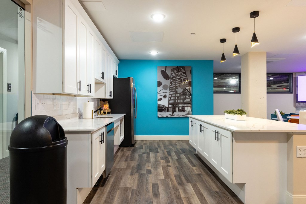 a kitchen with white cabinets and a blue wall