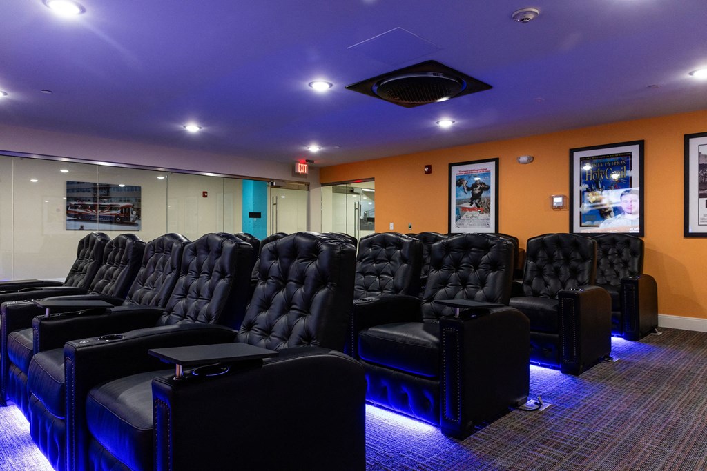 a cinema room with a row of black leather chairs and a projector screen