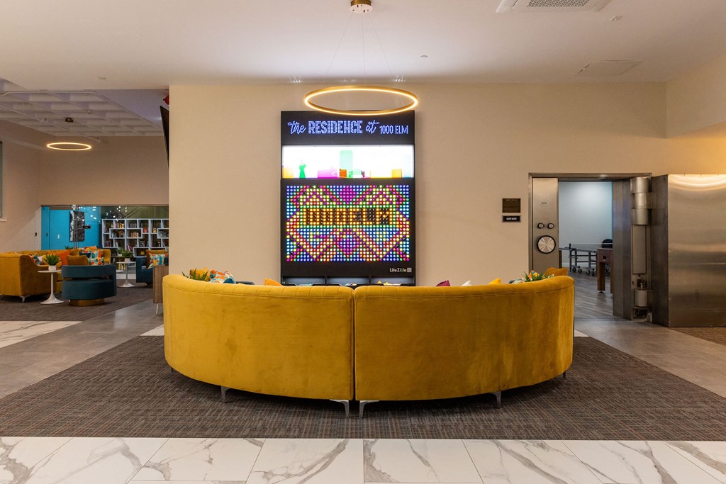 the lobby of a hotel with a large yellow couch in the center of the room