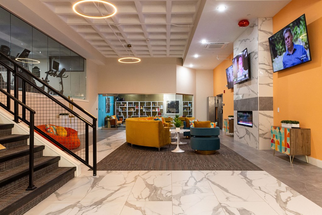 a lobby with couches and chairs and a tv on the wall