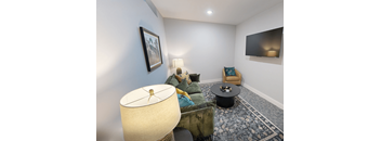 A living room with a sofa, a table, a lamp and a painting on the wall.