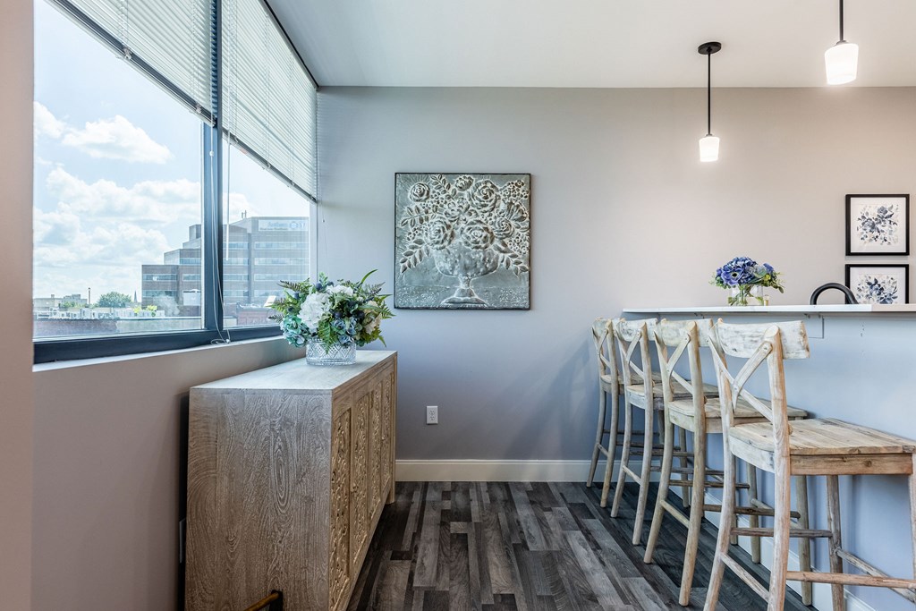 A room with a wooden cabinet, chairs, and a painting on the wall.