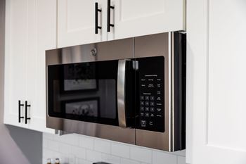 A stainless steel microwave oven with digital display and control panel.