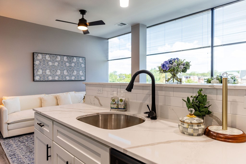 A modern kitchen with a white countertop and a large window.