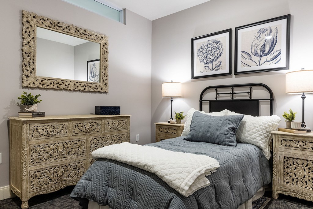 A bedroom with a bed, nightstands, and a mirror.