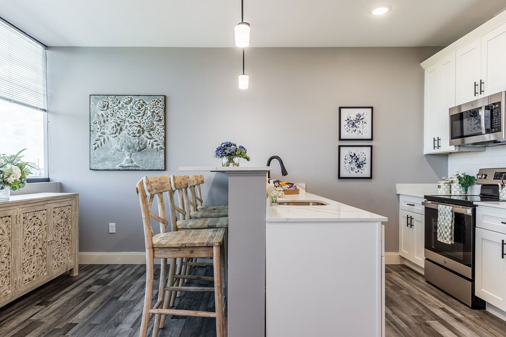 A kitchen with a white island and wooden chairs.